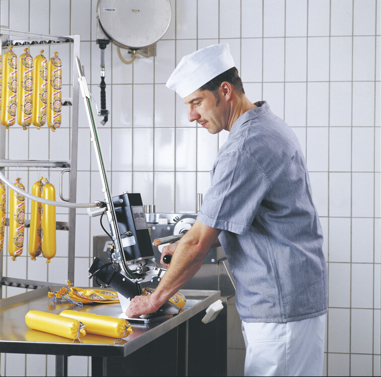 Butcher working with manual clipping machine